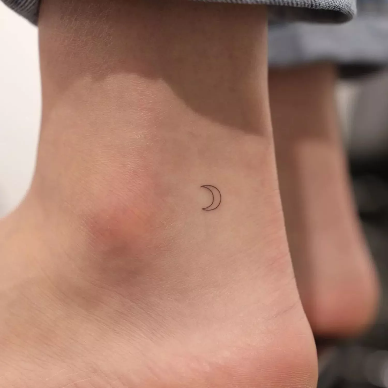tiny crescent moon tattoo on outer ankle 