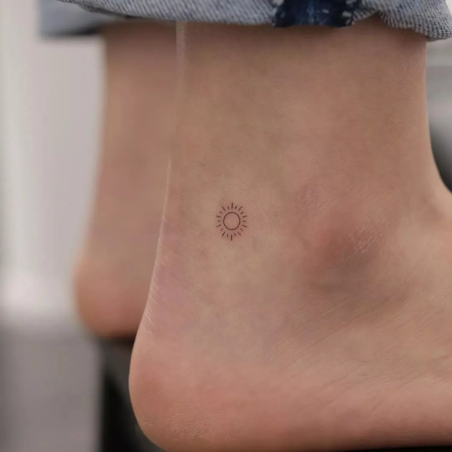 small sun tattoo on outer ankle 