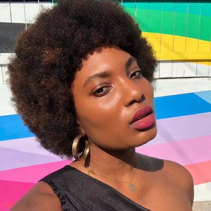 Byrdie writer Bianca Lambert wears an Afro hairstyle