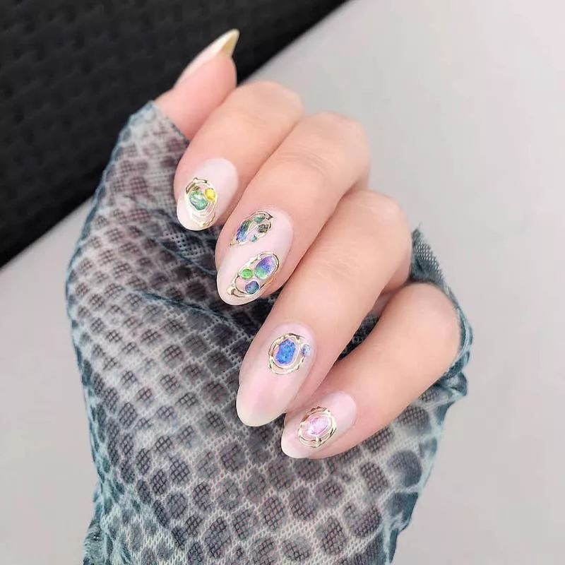 Pearlescent pink nails with metallic and colorful gem details
