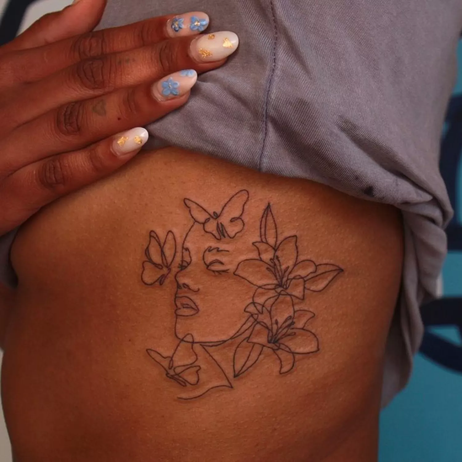 custom tattoo of face outline with butterflies and flowers