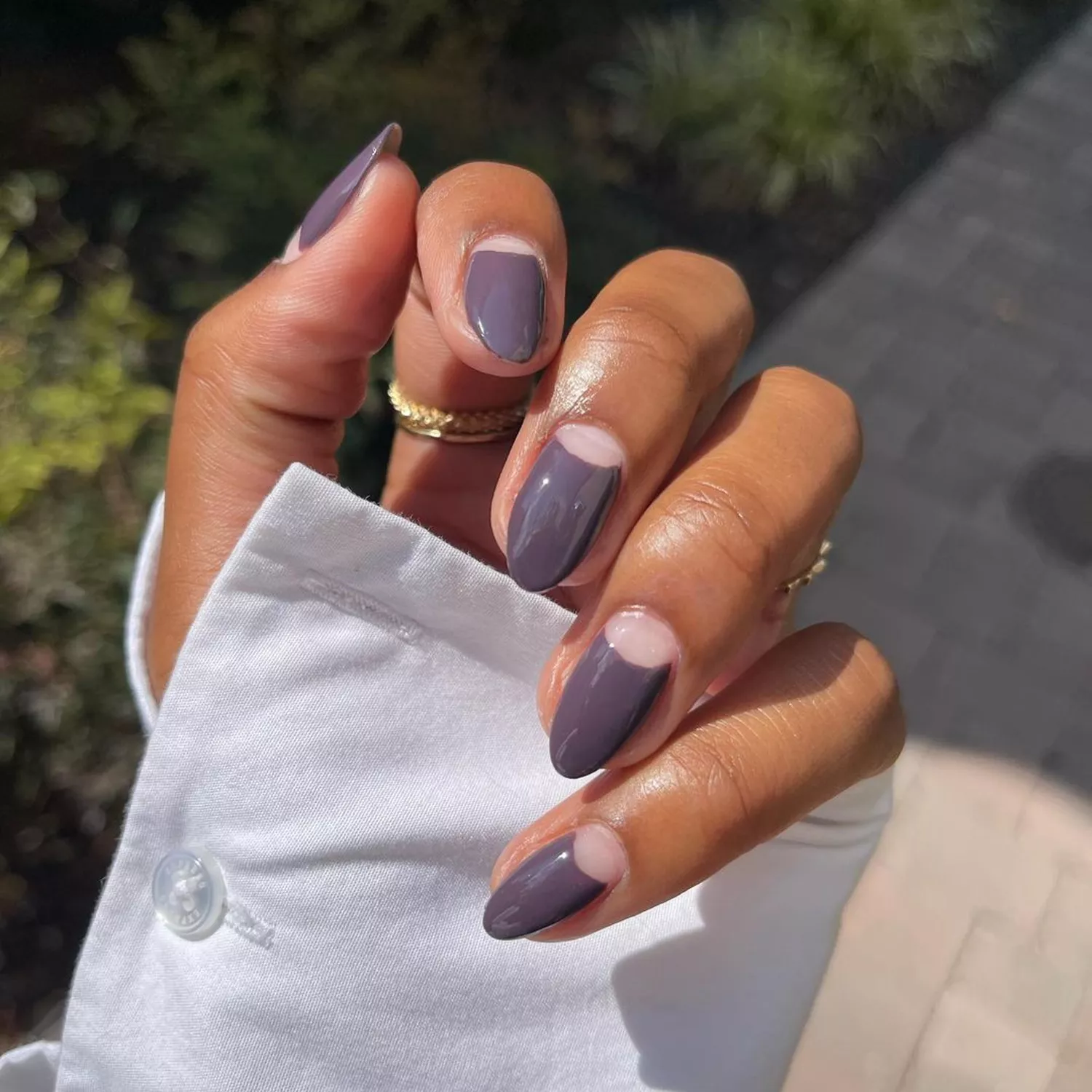 A manicure in a cool-toned shade with negative space half moons at the base