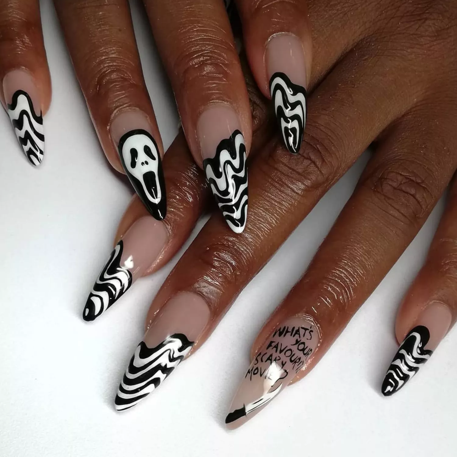 Stiletto shaped nails with black and white striped wavy French tips and hand-painted Ghostface art.