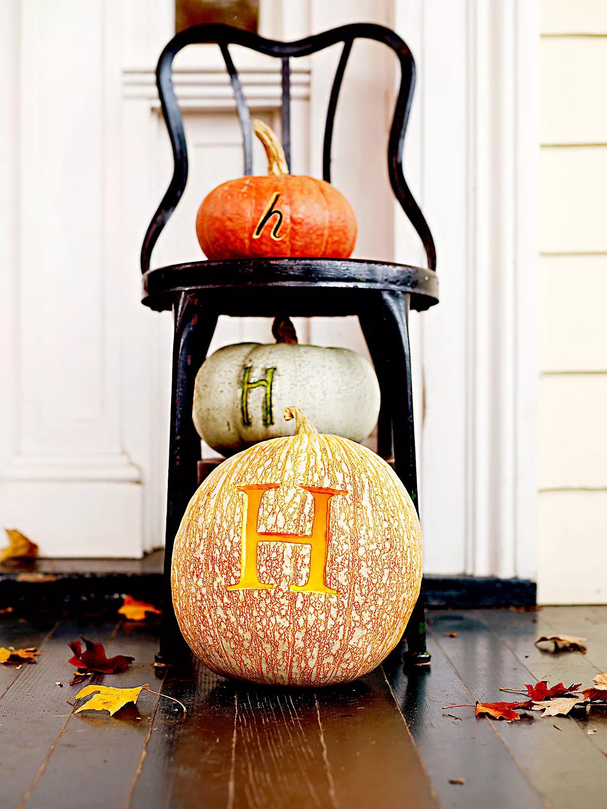 Three pumpkins with H carving on black chair