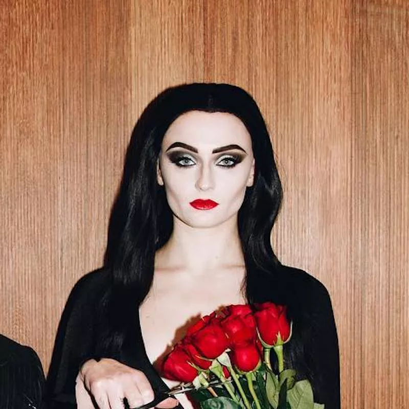 Sophie Turner wears a black and white Halloween makeup look with red lipstick