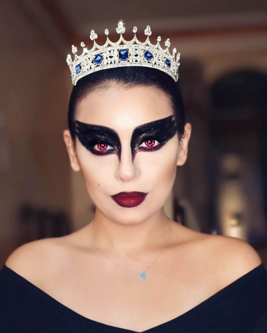 Makeup artist with Black Swan-inspired look, red contacts, and tiara