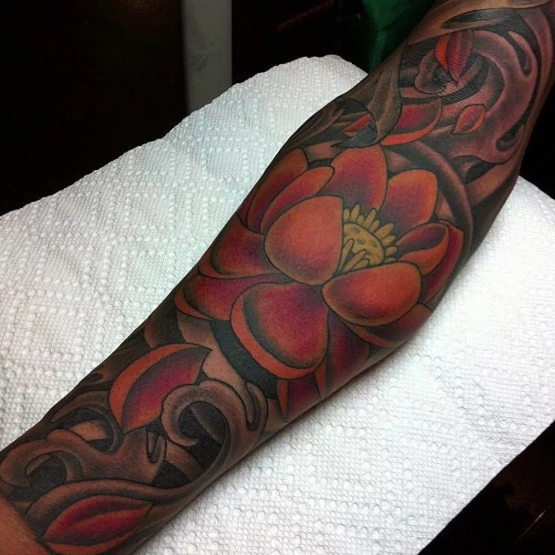 Image of an arm with an orange lotus flower tattoo
