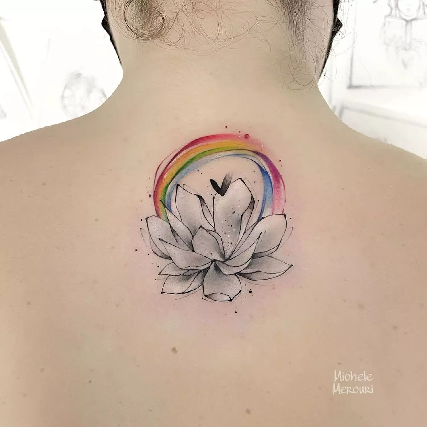 A lotus flower with a rainbow halo tattoo