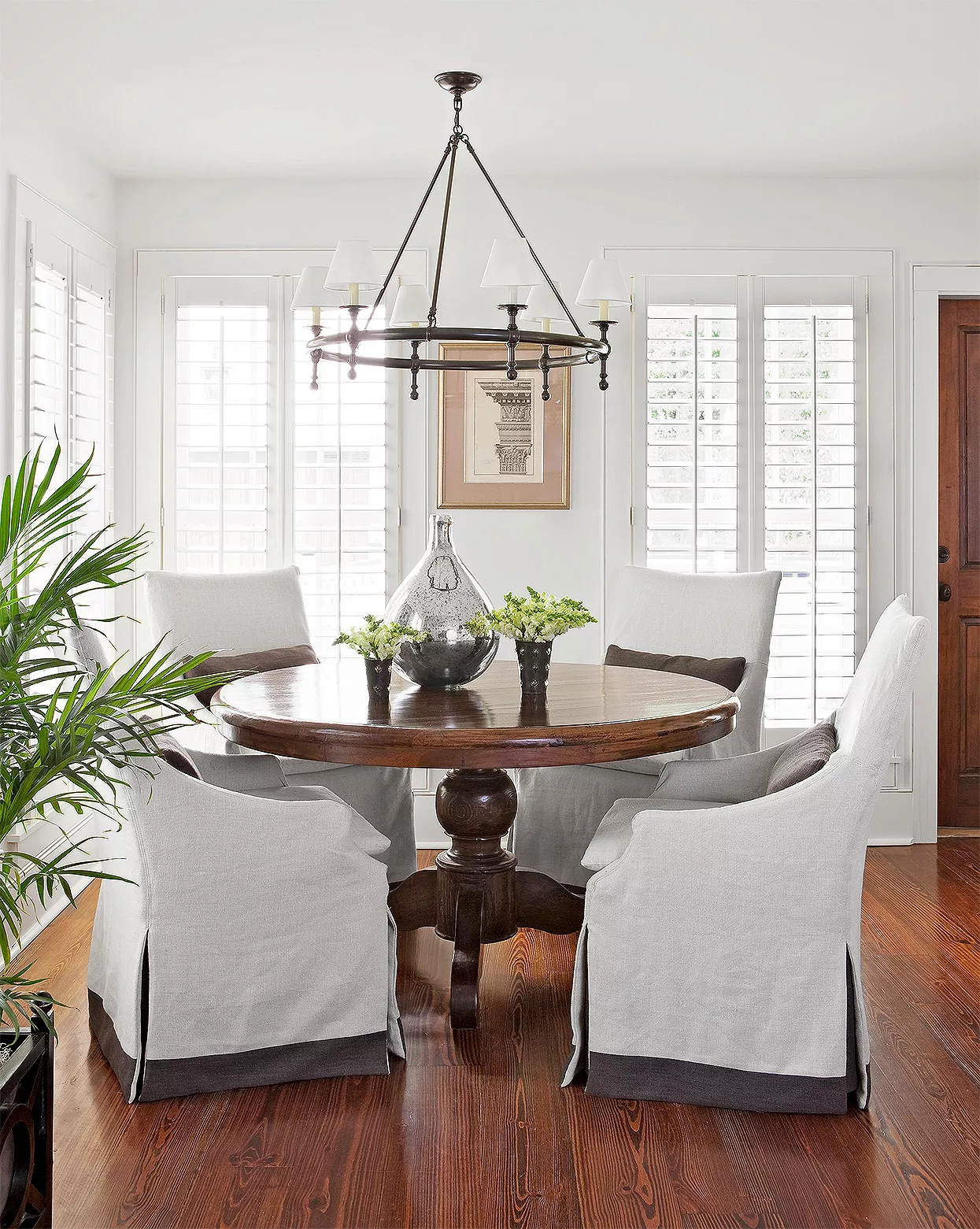 neutral slipcovered chairs surrounding traditional dining table under pendant