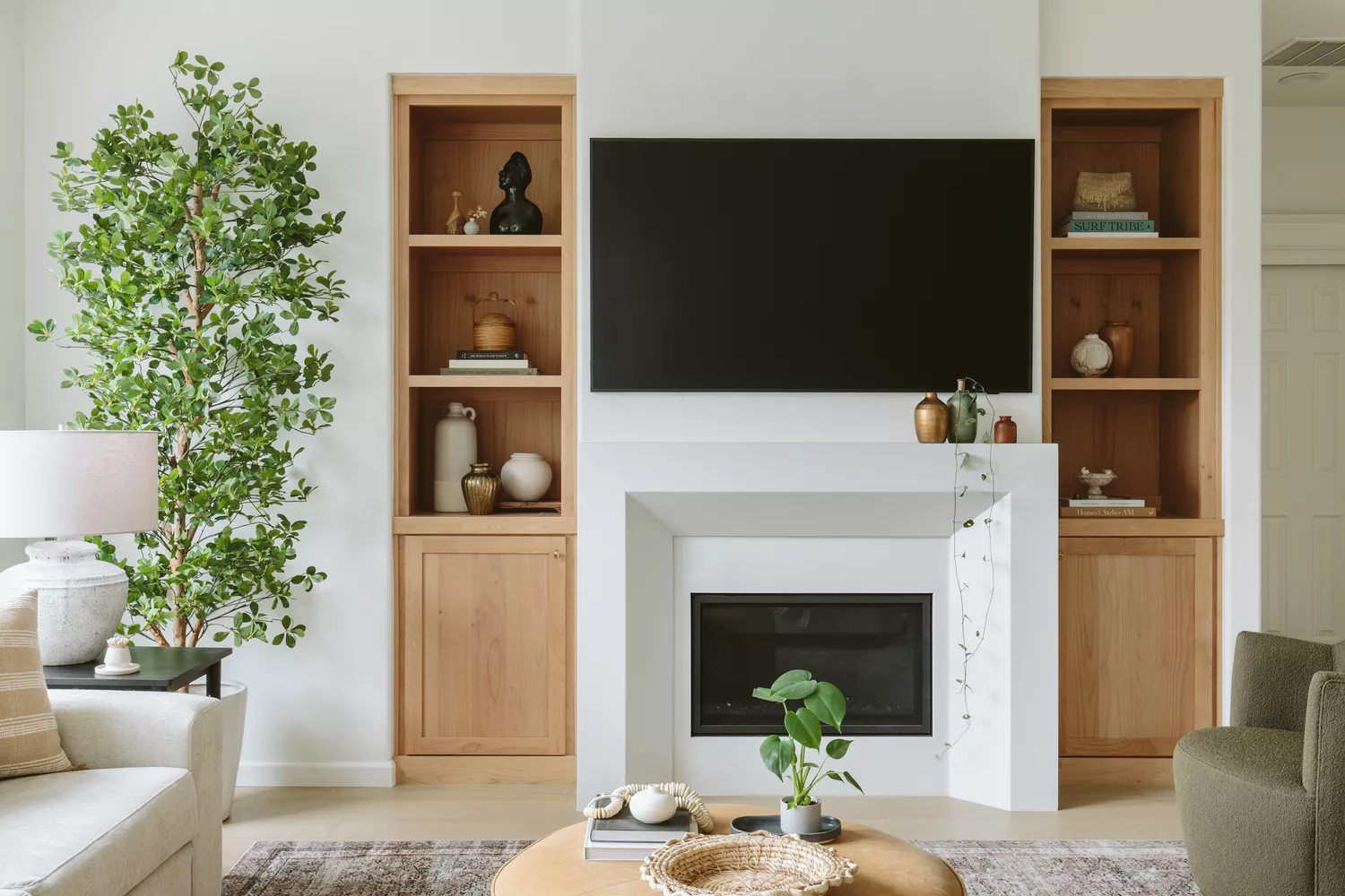 all white fireplace framed by neutral wood built-in